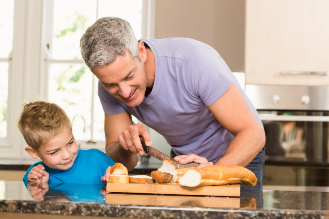 Father showing son how to slice bread