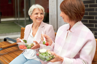 Two older women eating salad