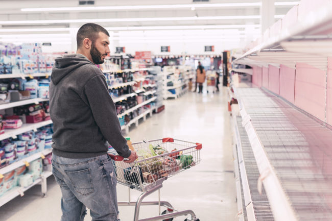 Man staring at empty supermarket shelves