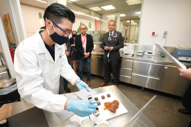 Isaac Goh gives out tasting samples of melaka flavored crunchy chocolate cubes to guests on the opening day of ADM's Plant-based Innovation Lab in Singapore