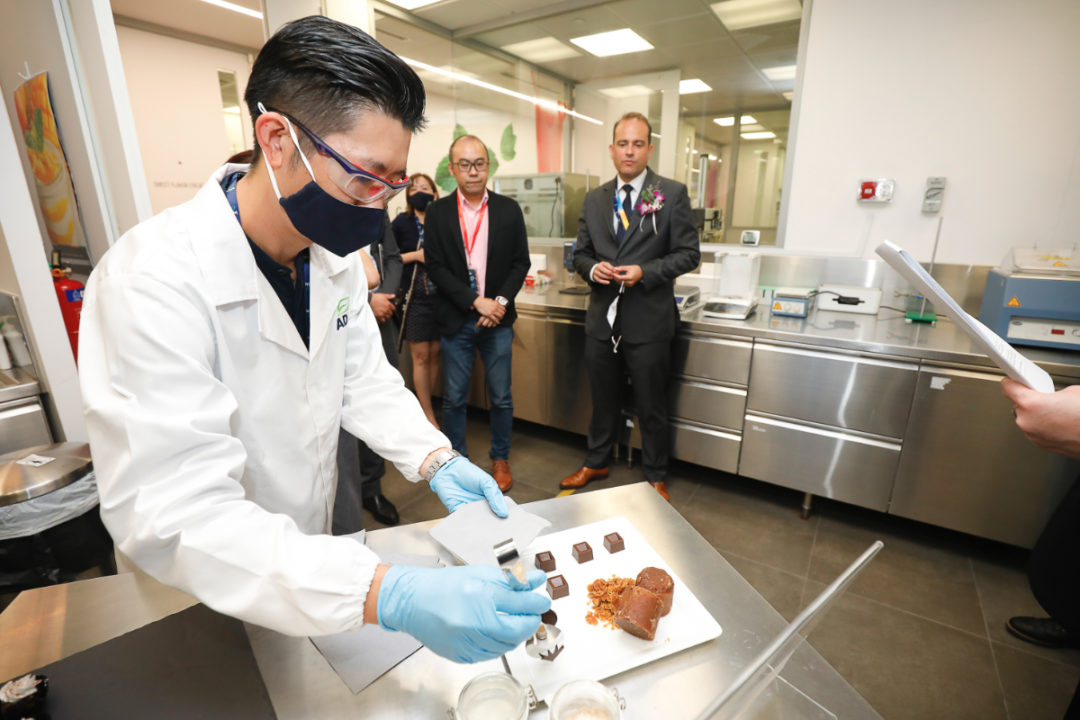 Isaac Goh gives out tasting samples of melaka flavored crunchy chocolate cubes to guests on the opening day of ADM's Plant-based Innovation Lab in Singapore