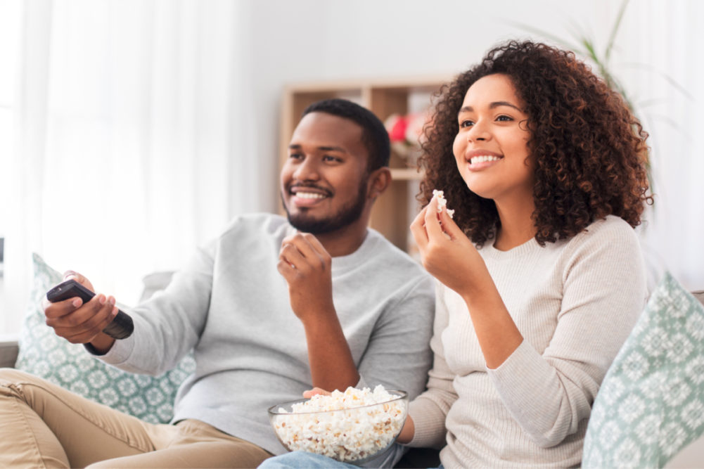 Couple eating popcorn while watching TV.