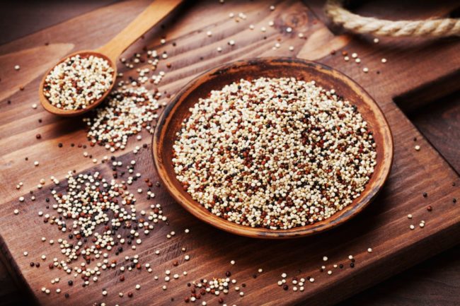 Bowl of dried quinoa, wooden cutting board
