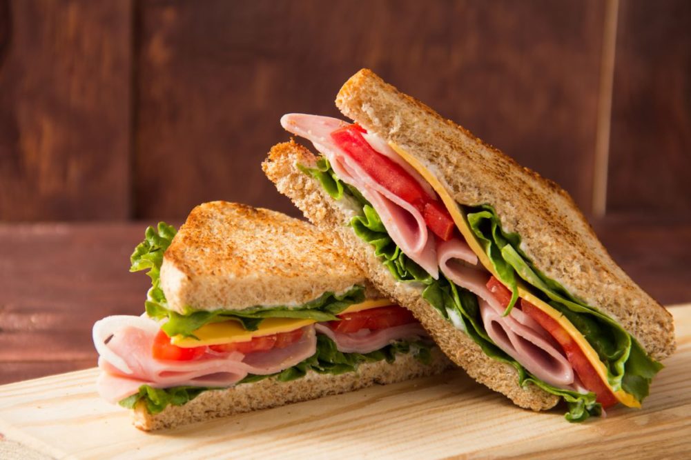 Ham and cheese sandwich, toasted bread, lettuce, tomato, wood cutting board