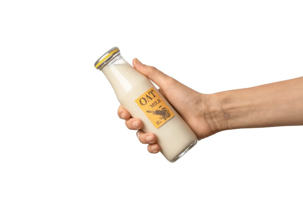 Hand holding oat milk bottle