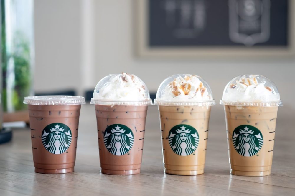 Four Starbucks drinks, three with whipped cream.