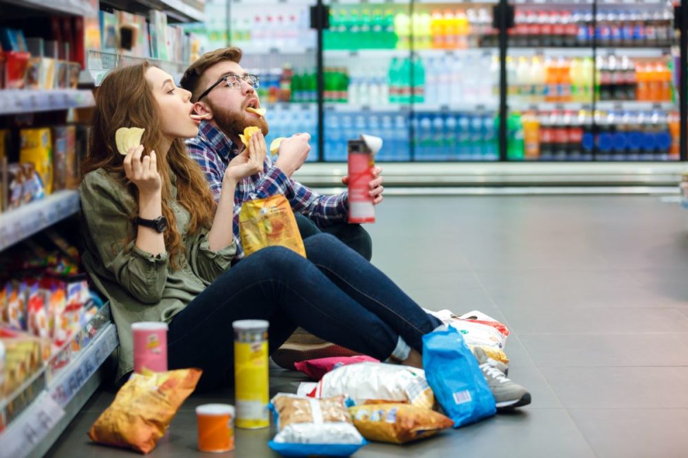 Couple eating snacks on grocery store floor