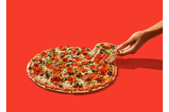 A deluxe thin crust pizza in front of a red screen
