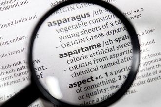 The word aspartame found in dictionary with magnifying glass. 