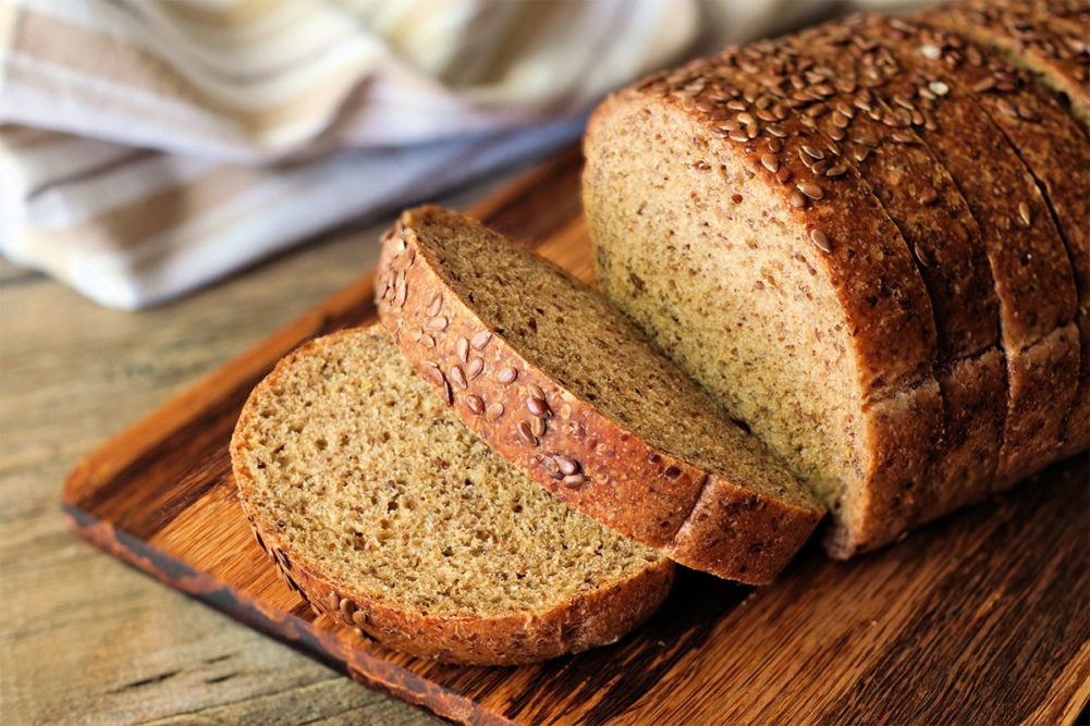 Loaf of whole grain bread on cutting board.
