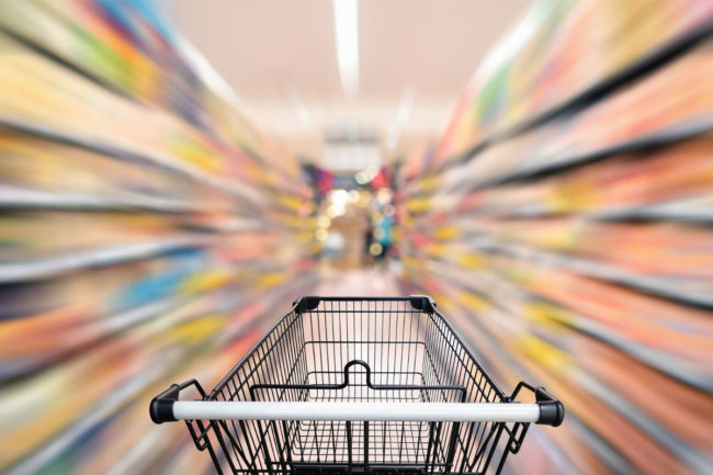 Grocery cart in blurry grocery aisle. 
