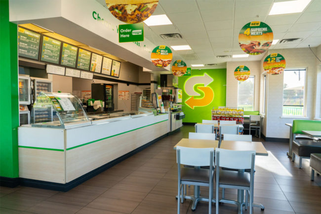 Inside of modern Subway restaurant with green walls. 