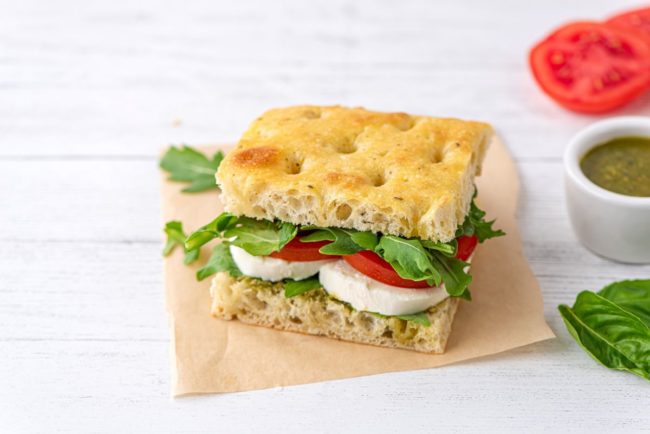 A piece of Rich focaccia with tomatoes, spinach and mozzarella. 