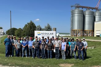 A group of Scoular employees stand outside of Illinois facility on sunny day. 