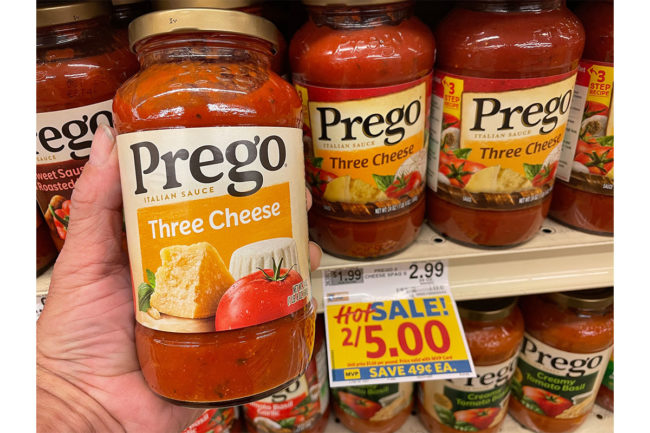 Hand holding Prego sauce in grocery store. 