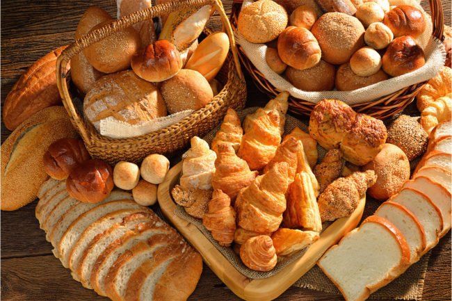 Variety of white breads and rolls in wicker basket. 