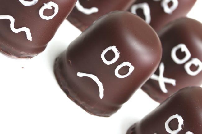 Chocolate drops with icing frowny faces drawn on. 