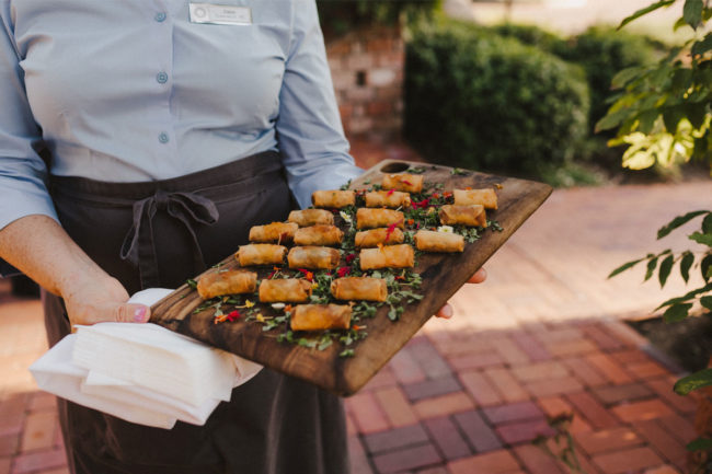 Server holding a tray of egg rolls. 