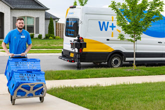 Walmart employee wheels groceries up driveway. 