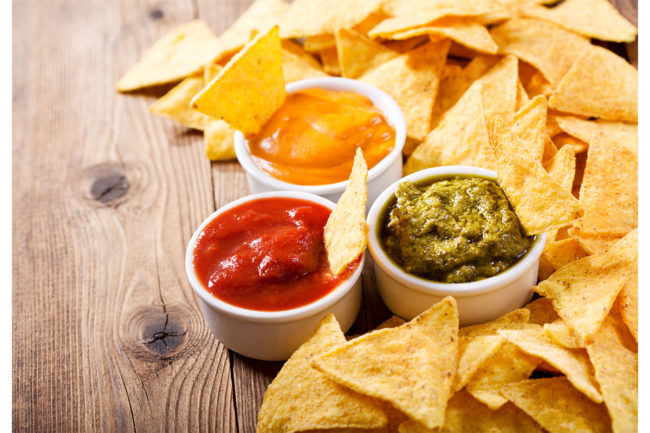 Tortilla chips with one red salsa and one green salsa. 