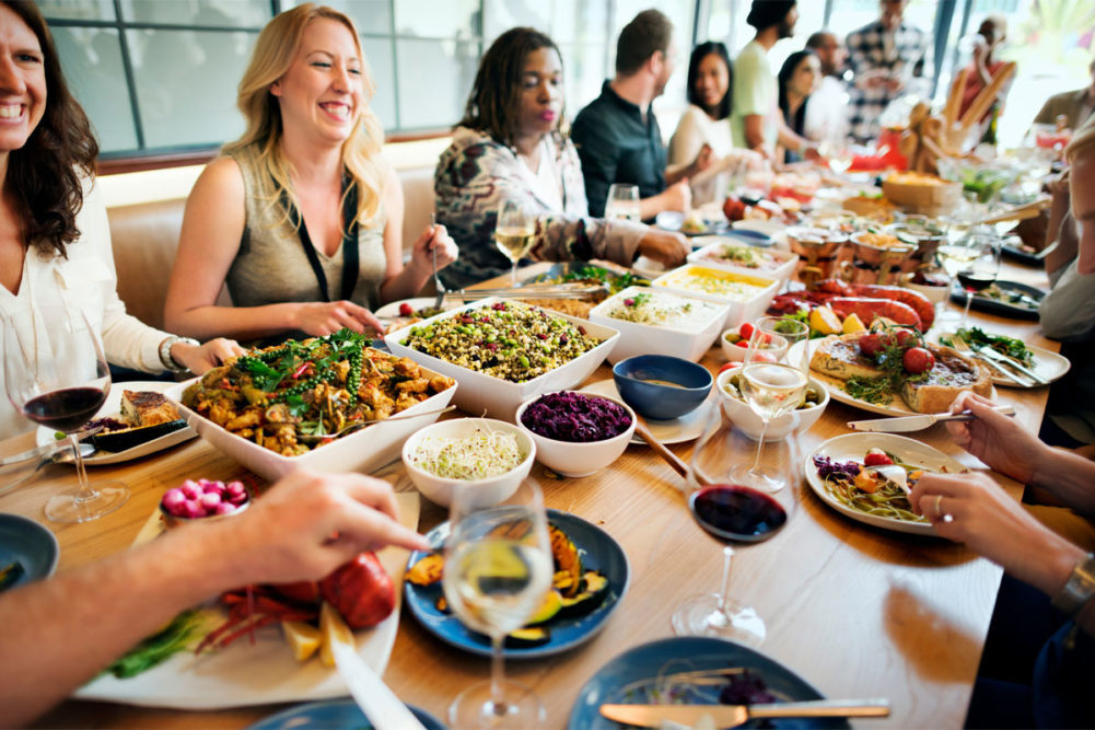 Group of people eating and drinking merrily at restaurant. 