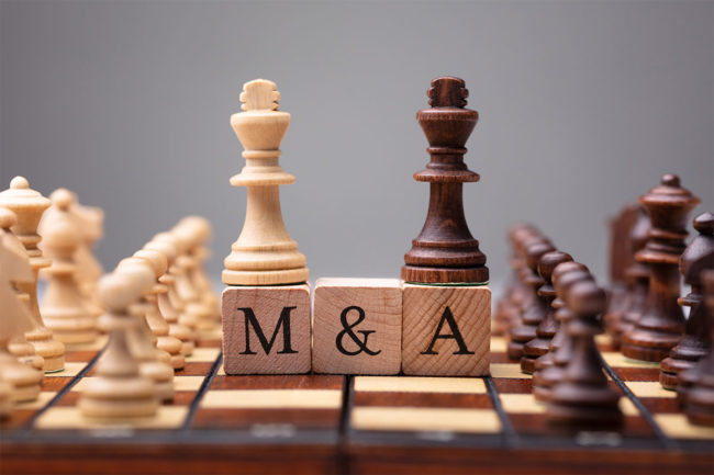 M&A on wooden blocks on a chess board. 