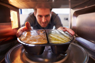 Man pulls frozen meal out of microwave.