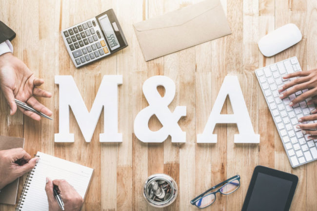 M&A letters on desk to suggest merger & acquisition.