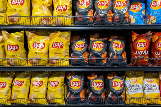 Assortment of Frito-Lay products on grocery store shelf. 