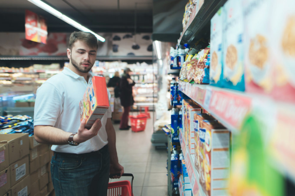 Man reading packaged food in grocery store